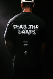 Person wearing a black t-shirt with 'FEAR THE LAMB' text on the back against a dark background