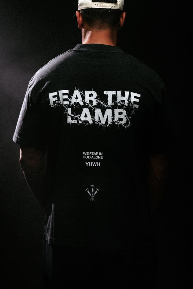 Person wearing a black t-shirt with 'FEAR THE LAMB' text on the back against a dark background