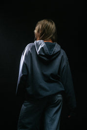 Person wearing a dark blue hoodie on a black background