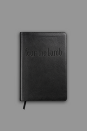 Black book with 'fear the lamb' embossed on the cover against a gray background