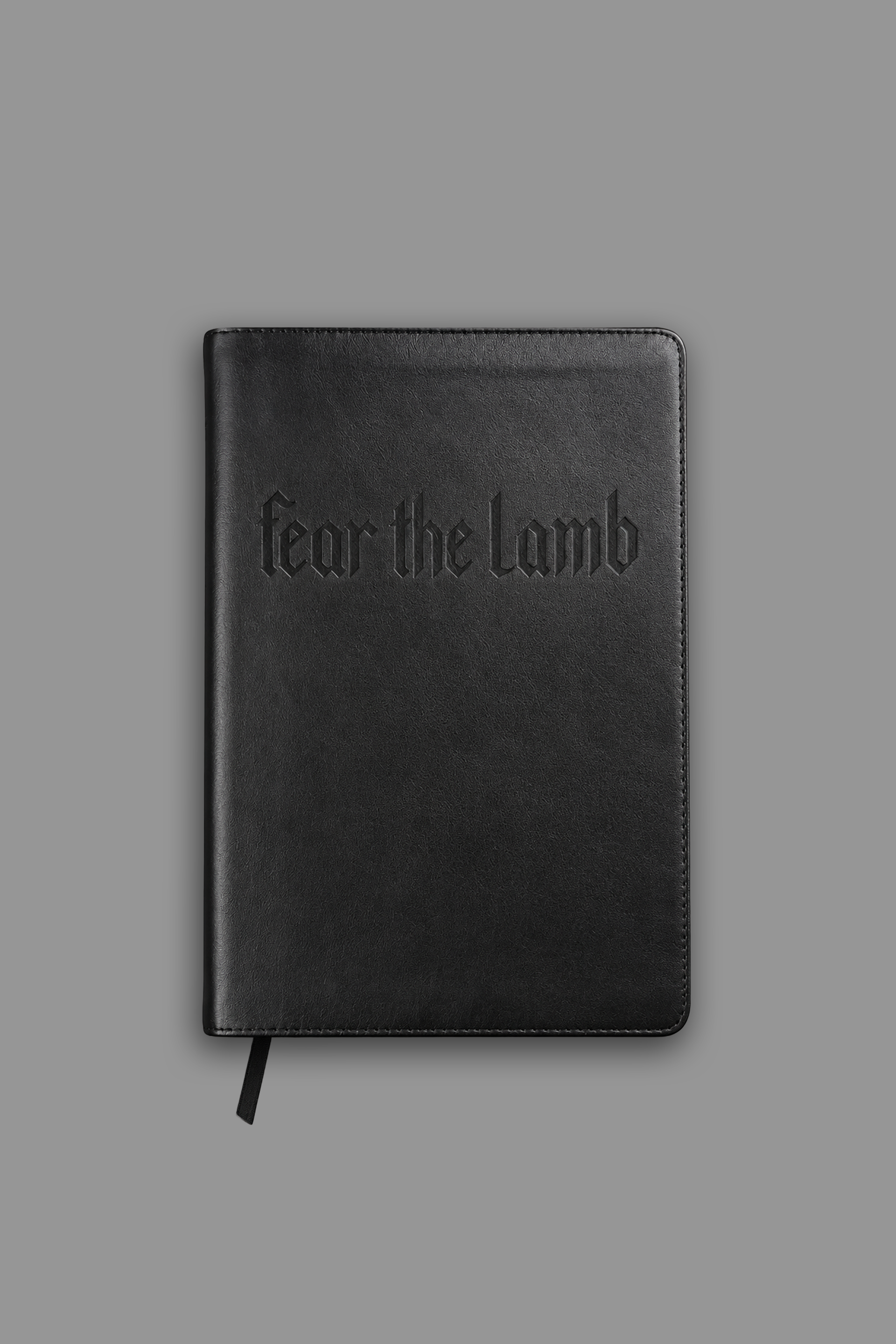 Black book with 'fear the lamb' embossed on the cover against a gray background